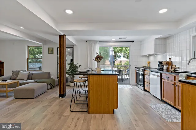a kitchen with kitchen island granite countertop wooden floors and wide window
