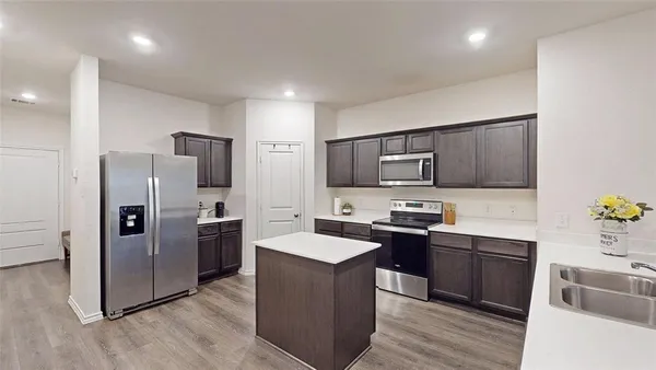 a kitchen with granite countertop stainless steel appliances a sink a counter top space and cabinets