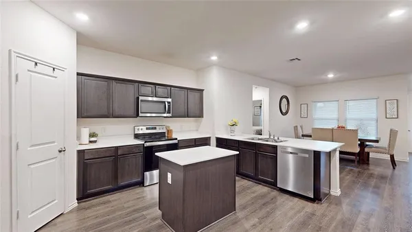 a kitchen with lots of white cabinets appliances and sink