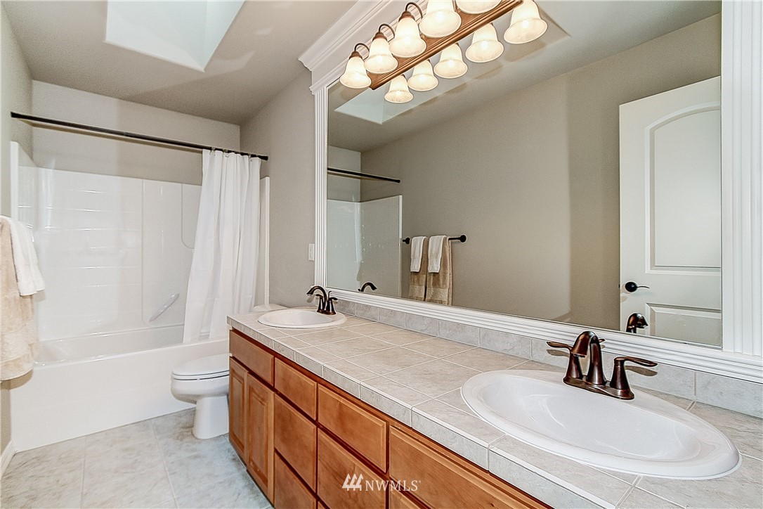 4004 215th Street Southeast Bothell, WA 98021 - Photo 19 of 25 a bathroom with a sink a toilet a mirror and shower