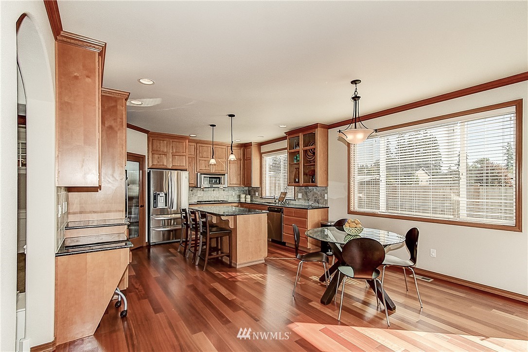 4004 215th Street Southeast Bothell, WA 98021 - Photo 9 of 25 a open kitchen with stainless steel appliances granite countertop a refrigerator a stove a dining table and chairs with wooden floor
