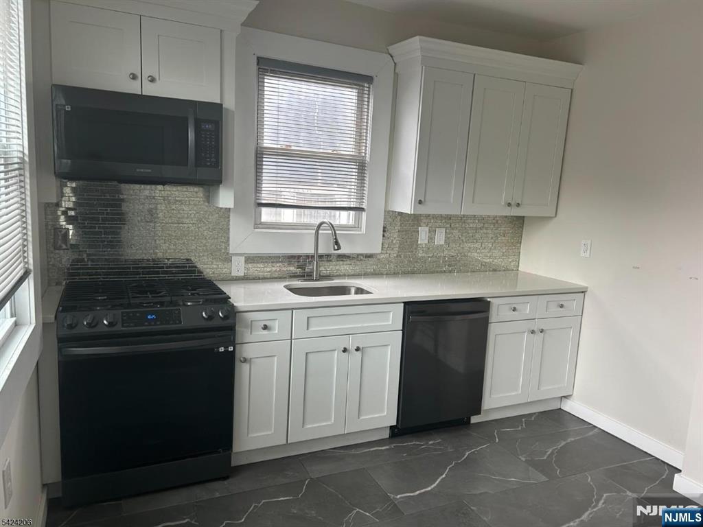 194-196 Wainwright Street Newark, NJ 07112 - Photo 2 of 6 a kitchen with white cabinets and black appliances