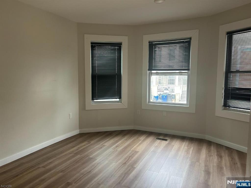 194-196 Wainwright Street Newark, NJ 07112 - Photo 6 of 6 a view of an empty room with wooden floor and a window