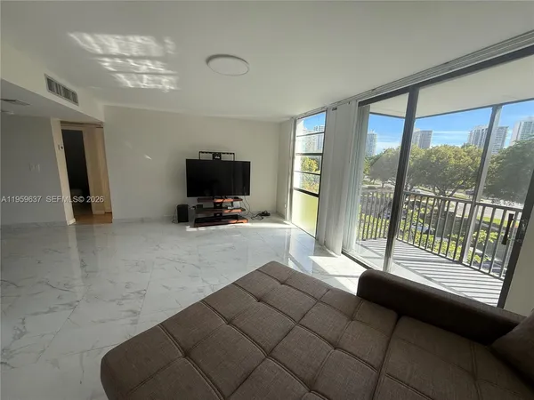 a living room with furniture a flat screen tv and a floor to ceiling window