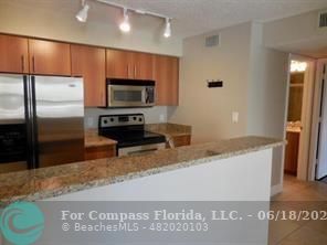 1020 Crystal Way, Unit D Delray Beach, FL 33444 - Photo 17 of 24 a kitchen with granite countertop a refrigerator and a stove