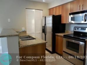 1020 Crystal Way, Unit D Delray Beach, FL 33444 - Photo 18 of 24 a kitchen with granite countertop a stove and a refrigerator
