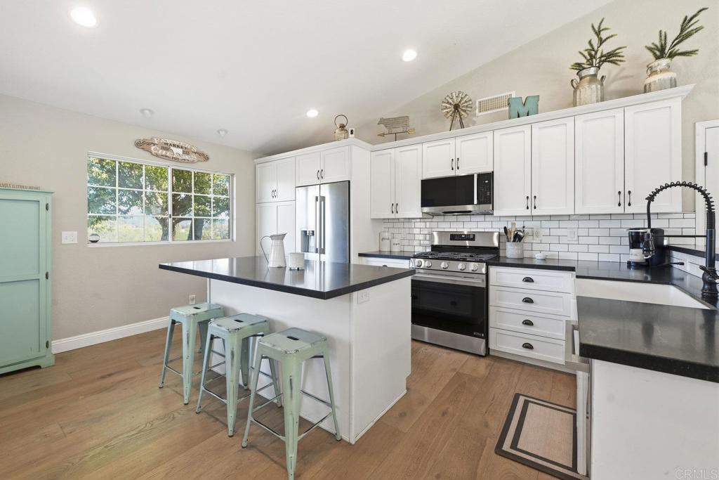 13638 West Oak Glen Road Valley Center, CA 92082 - Photo 2 of 30 a kitchen with granite countertop a stove top oven a sink dishwasher a dining table and chairs with wooden floor