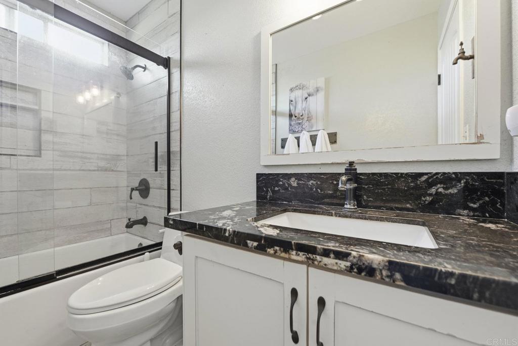 13638 West Oak Glen Road Valley Center, CA 92082 - Photo 24 of 30 a bathroom with a granite countertop sink a toilet a mirror and shower