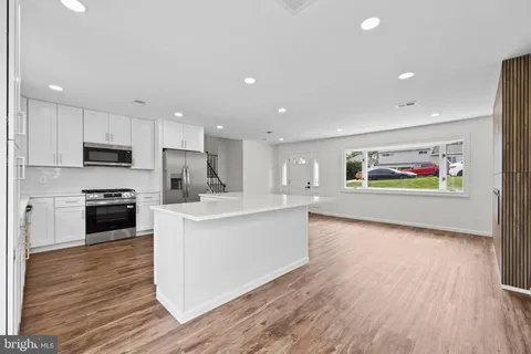 a large kitchen with stainless steel appliances a large counter top a stove and a refrigerator