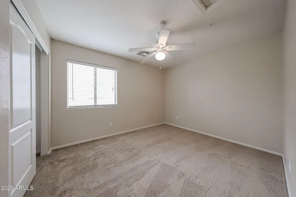 an empty room with chandelier fan and windows