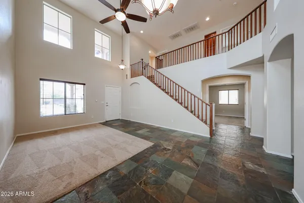 an empty room with windows and chandelier fan