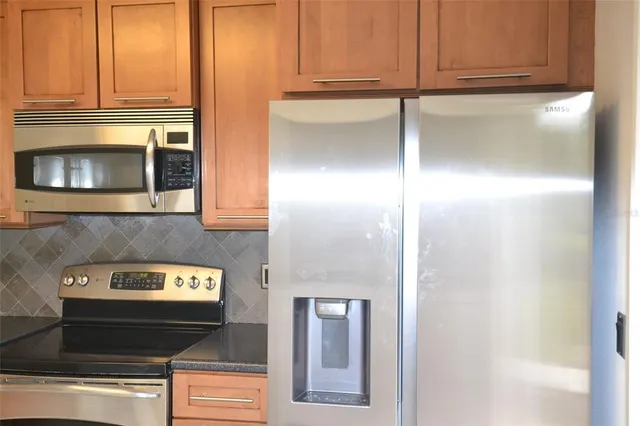 a kitchen with stainless steel appliances granite countertop a refrigerator and a stove