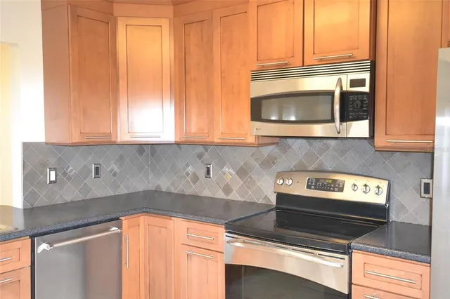 a kitchen with granite countertop cabinets stainless steel appliances and a counter space