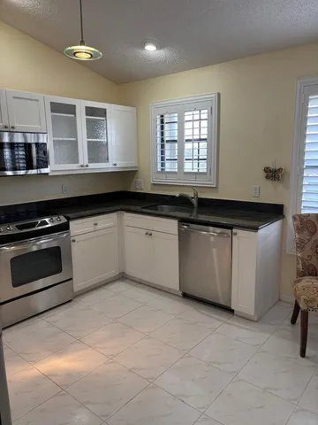 a large kitchen with granite countertop a stove a sink dishwasher and a microwave
