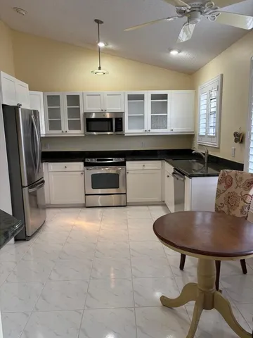 a kitchen with stainless steel appliances granite countertop a sink a stove a refrigerator a dining table and chairs