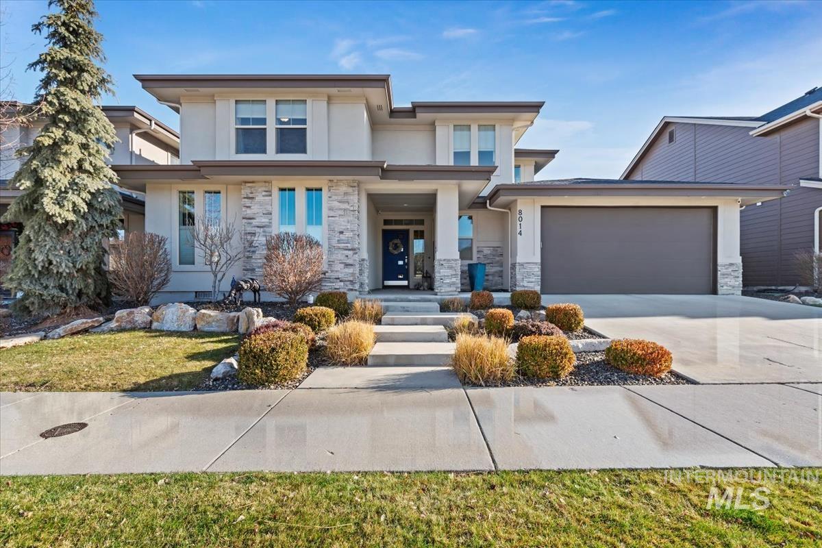 Prairie-style home featuring stucco siding, concrete driveway, and stone siding