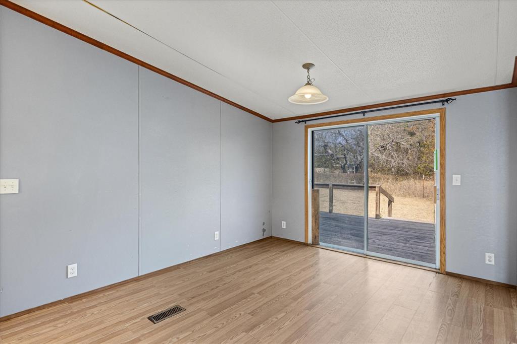 2903 Centaurus Way Granbury, TX 76048 - Photo 20 of 31 Spare room featuring ornamental molding, light wood-style floors, and a textured ceiling