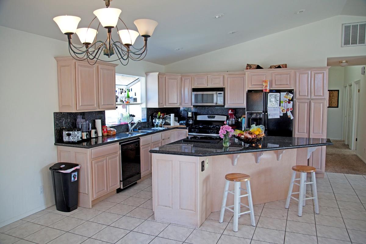 4854 8th Street Carpinteria, CA 93013 - Photo 4 of 8 a kitchen with stainless steel appliances granite countertop a sink a stove a refrigerator cabinets and chairs