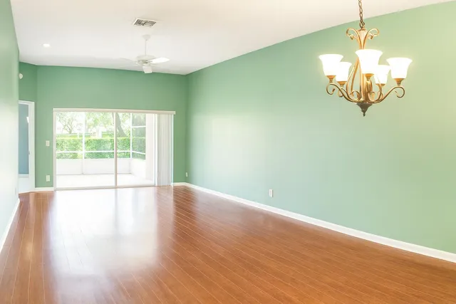 a view of a room with wooden floor chandelier and a window