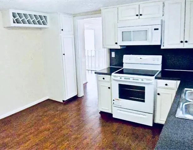 a kitchen with granite countertop white cabinets and white appliances