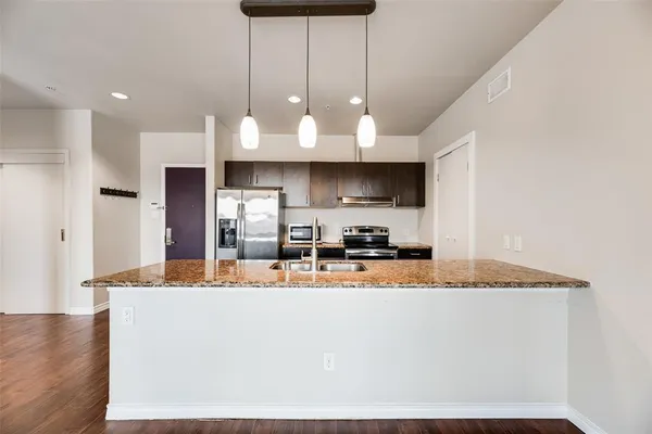a kitchen with stainless steel appliances granite countertop a sink a stove and a refrigerator