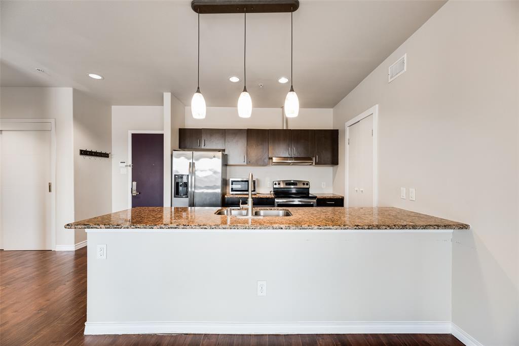 a kitchen with stainless steel appliances granite countertop a sink a stove and a refrigerator