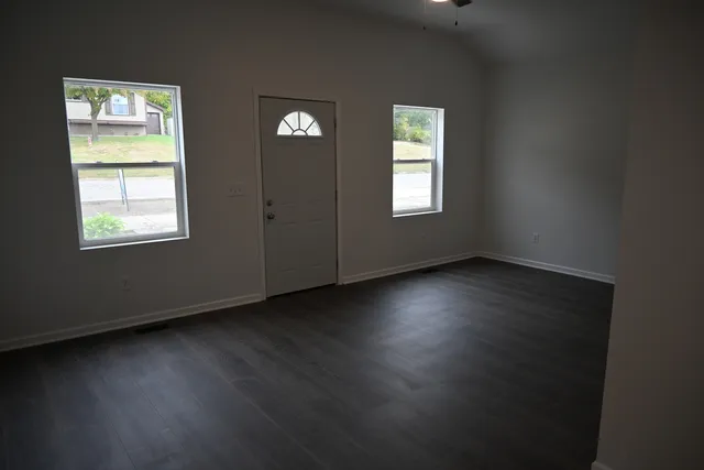a view of an empty room with wooden floor and a window