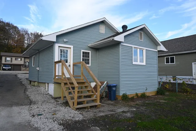 a backyard of a house with wooden fence and a chairs