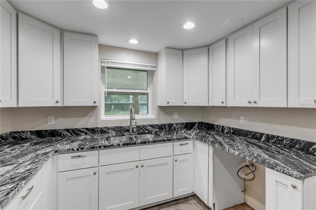 103 Flagler Avenue Edgewater, FL 32132 - Photo 29 of 53 a kitchen with granite countertop white cabinets and white appliances