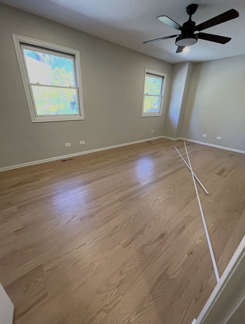 1703 Winnetka Road Northfield, IL 60093 - Photo 7 of 10 an empty room with wooden floor fan and windows