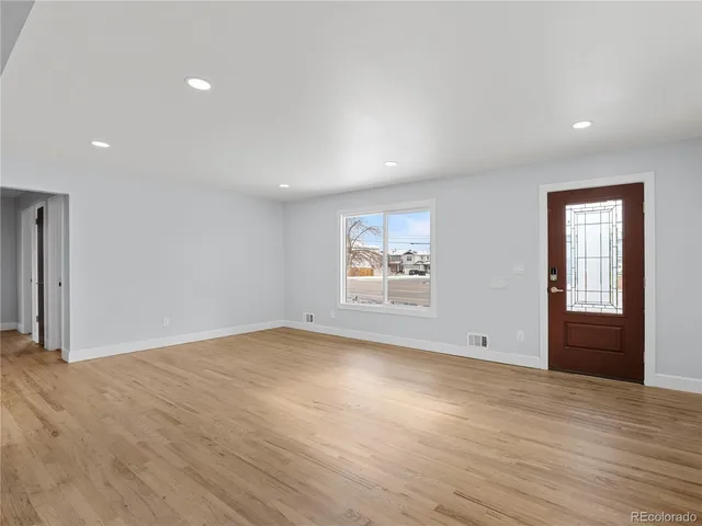 an empty room with windows fireplace and wooden floor