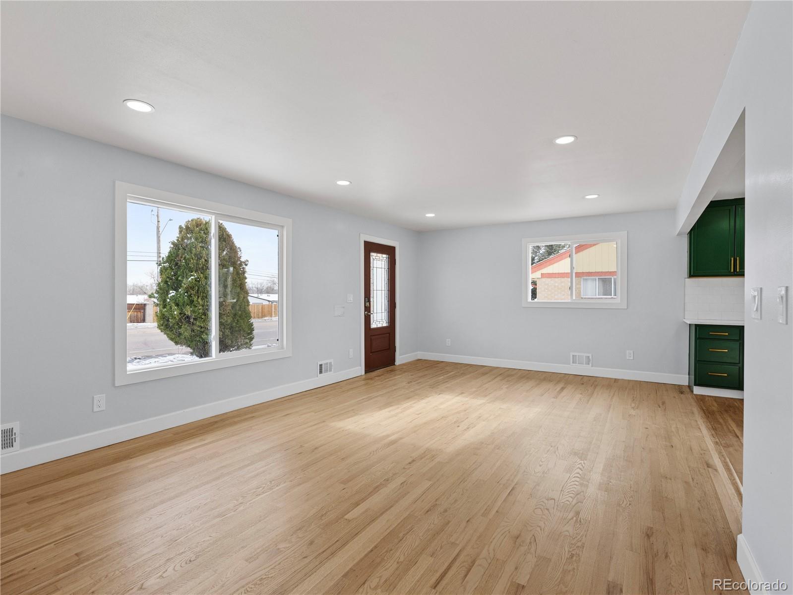 7889 North Pecos Street Denver, CO 80221 - Photo 13 of 42 an empty room with windows fireplace and wooden floor