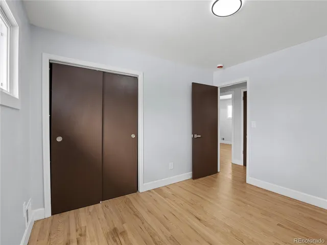 an empty room with wooden floor and window
