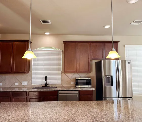a kitchen with stainless steel appliances wooden cabinets a refrigerator and a sink