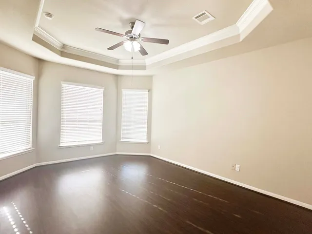 an empty room with wooden floor fan and windows