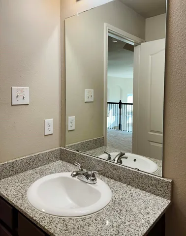 a bathroom with a granite countertop sink and a mirror