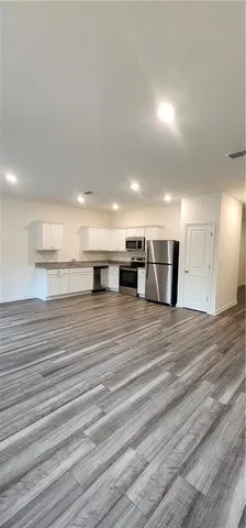 a large kitchen with a center island wooden floor stainless steel appliances and cabinets