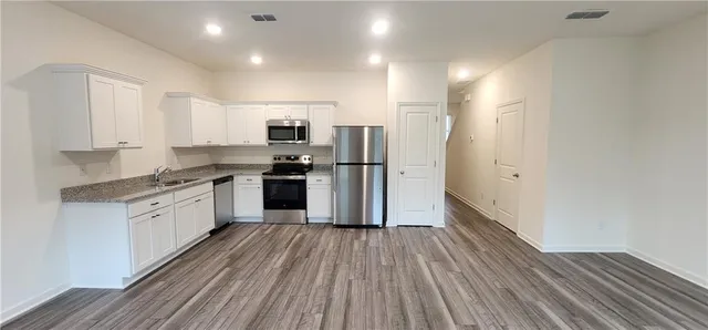 an empty room with kitchen view and a fireplace