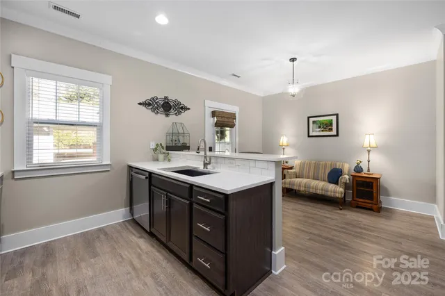 a kitchen with kitchen island granite countertop a sink dishwasher a stove and a dining table with wooden floor