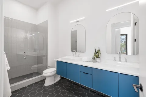 a bathroom with a double vanity sink toilet mirror and shower