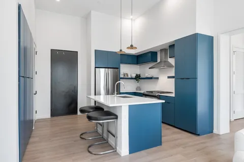 a kitchen with kitchen island stainless steel appliances a sink cabinets and wooden floor