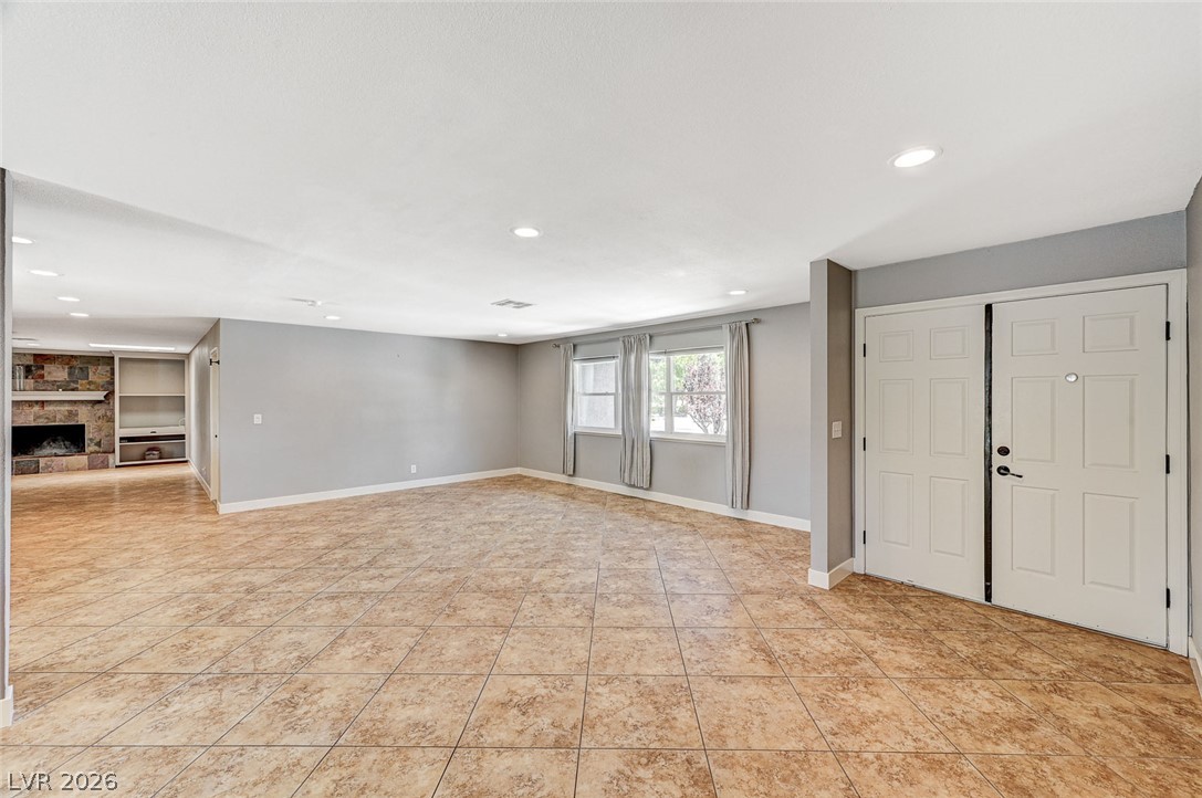 4153 Woodcrest Road Las Vegas, NV 89121 - Photo 6 of 58 A spacious living room featuring warm tile flooring and a rustic stone fireplace.