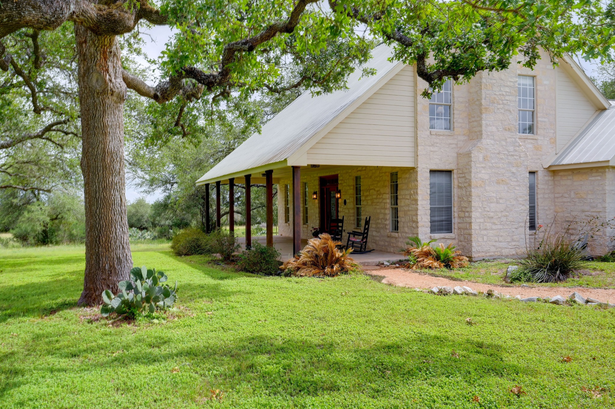 364 Nameless Road Driftwood, TX 78619 - Photo 4 of 32 A welcoming stone and siding residence, nestled amongst mature trees with a deep, inviting front porch.