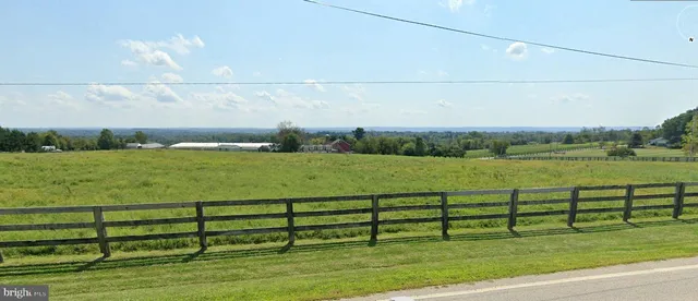a view of a green field with wooden fence