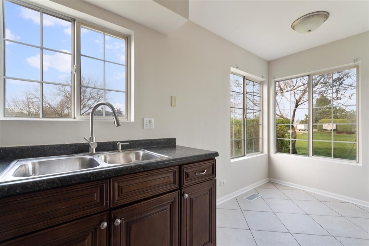 1171 Longford Road Bartlett, IL 60103 - Photo 8 of 22 a kitchen with a sink wooden cabinets and a large window