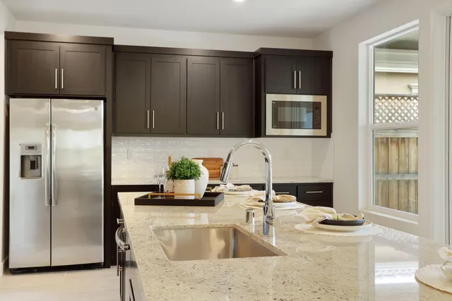 a kitchen with granite countertop a refrigerator and a stove top oven
