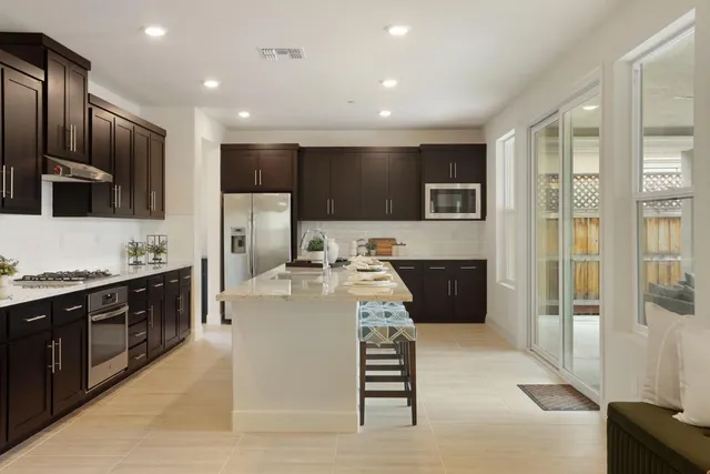 a large kitchen with stainless steel appliances a large counter top a stove a refrigerator and a sink