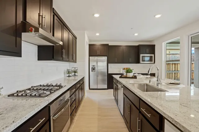 a large kitchen with stainless steel appliances granite countertop a sink stove and refrigerator