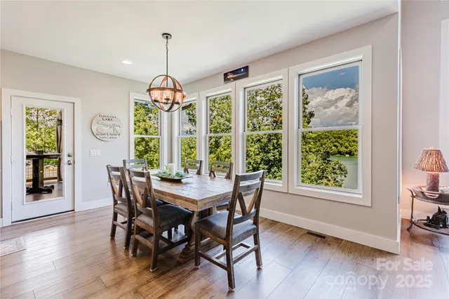 a dining room with wooden floor a chandelier a wooden table and chairs