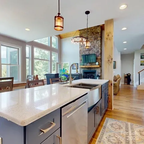 a large kitchen with stainless steel appliances a large counter top a stove and a chandelier